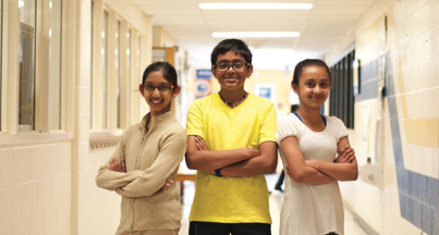 Students standing in hallway with arms crossed. Students standing in hallway with arms crossed.